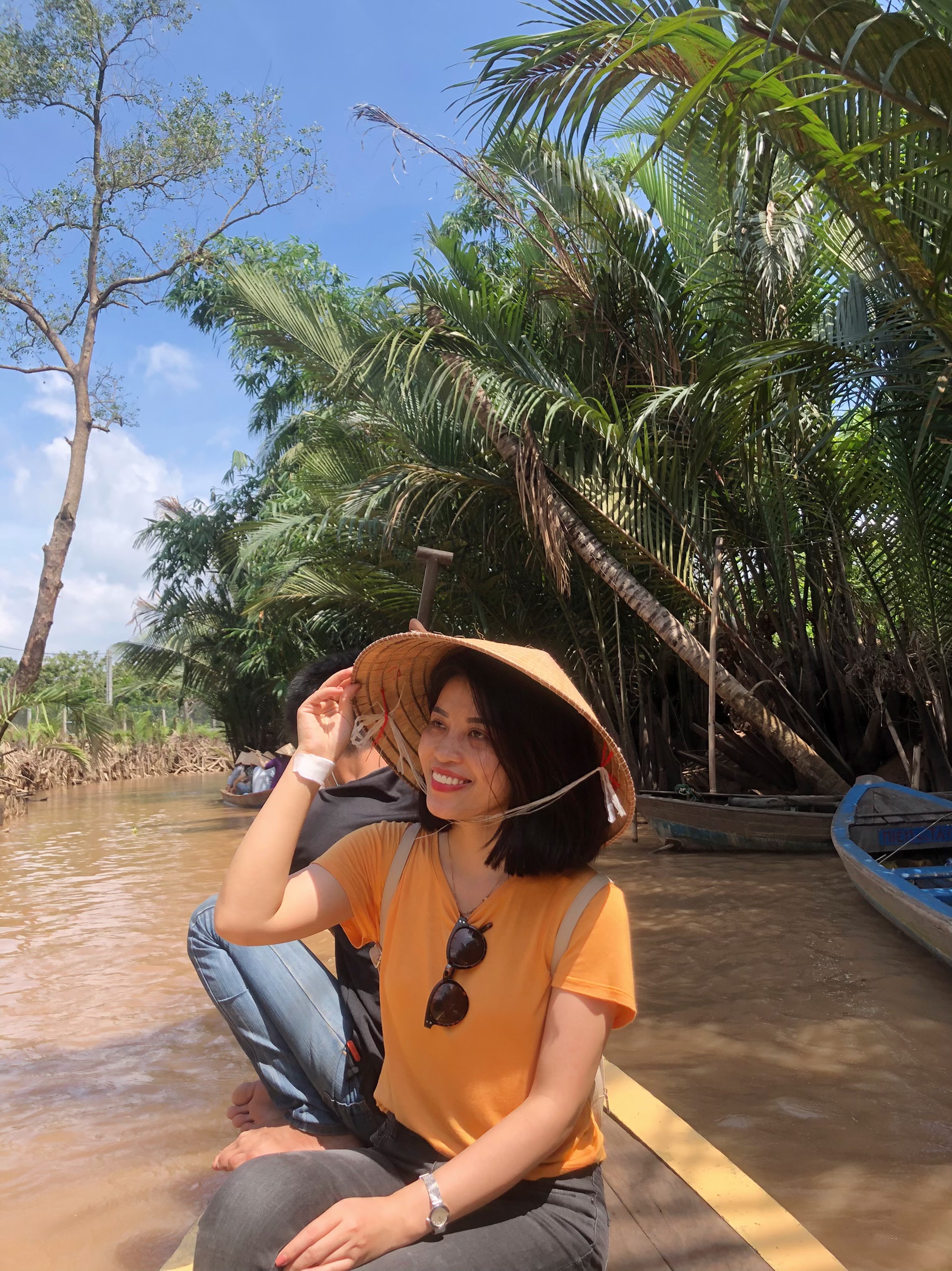 Image of Vietnamese student in Vietnam on a river with palm trees in the back