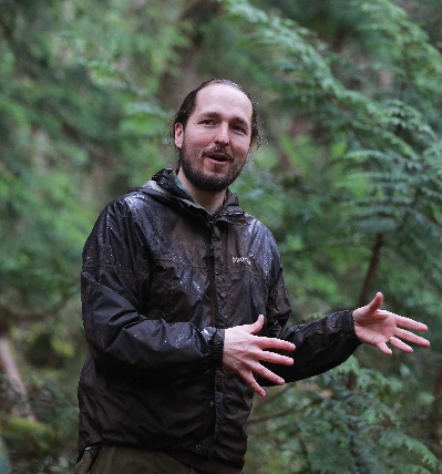 Dr. Lee Beavington instructing in a field-school setting in a deciduous forest