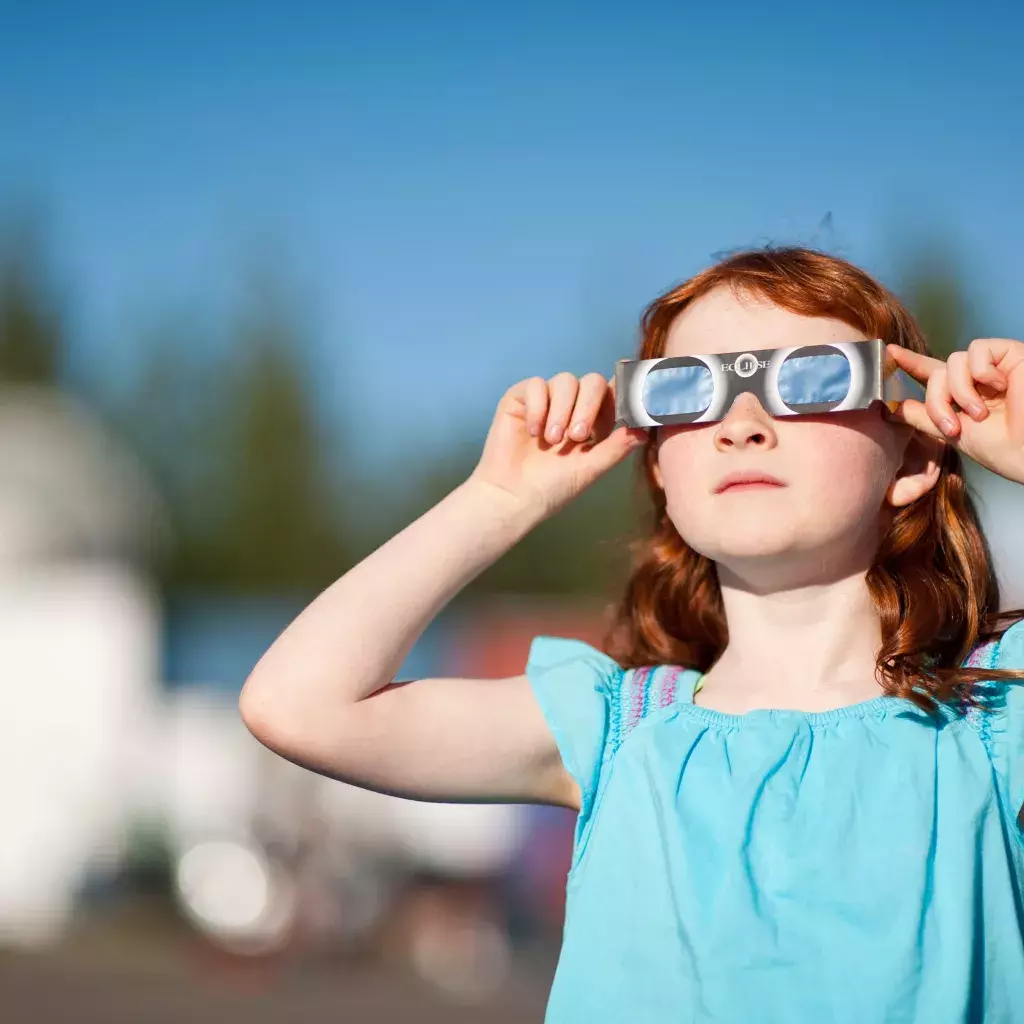 A child viewing an eclipse with special solar viewing glasses.