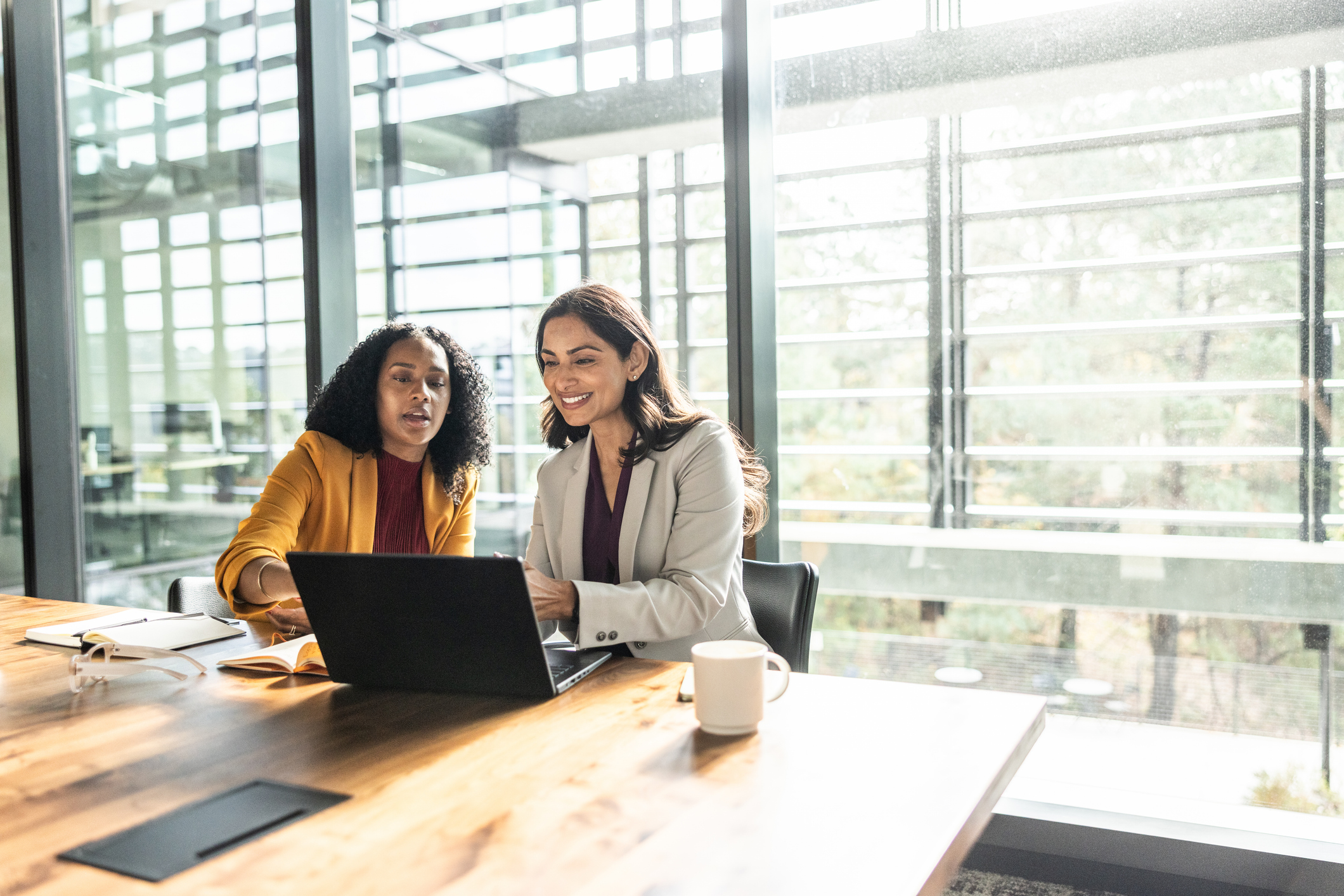 Two business women working together on a laptop at a table.