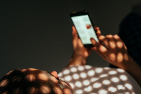 Woman using smart phone while lying on a bed at home.