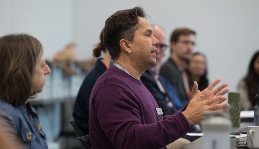 people sitting at a table in profile, person speaking is using them hands 