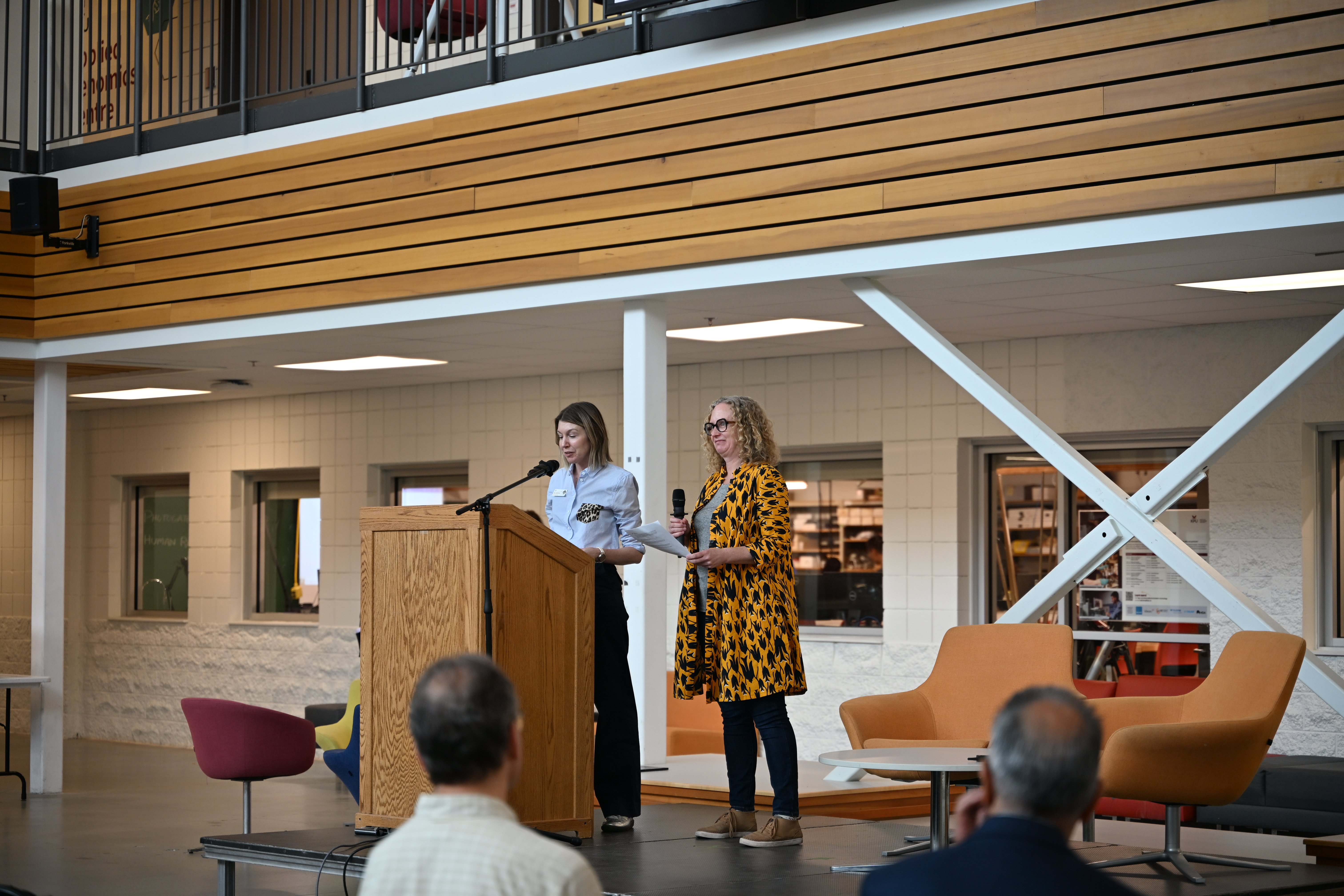 two researcher collaborators present on stage at podium