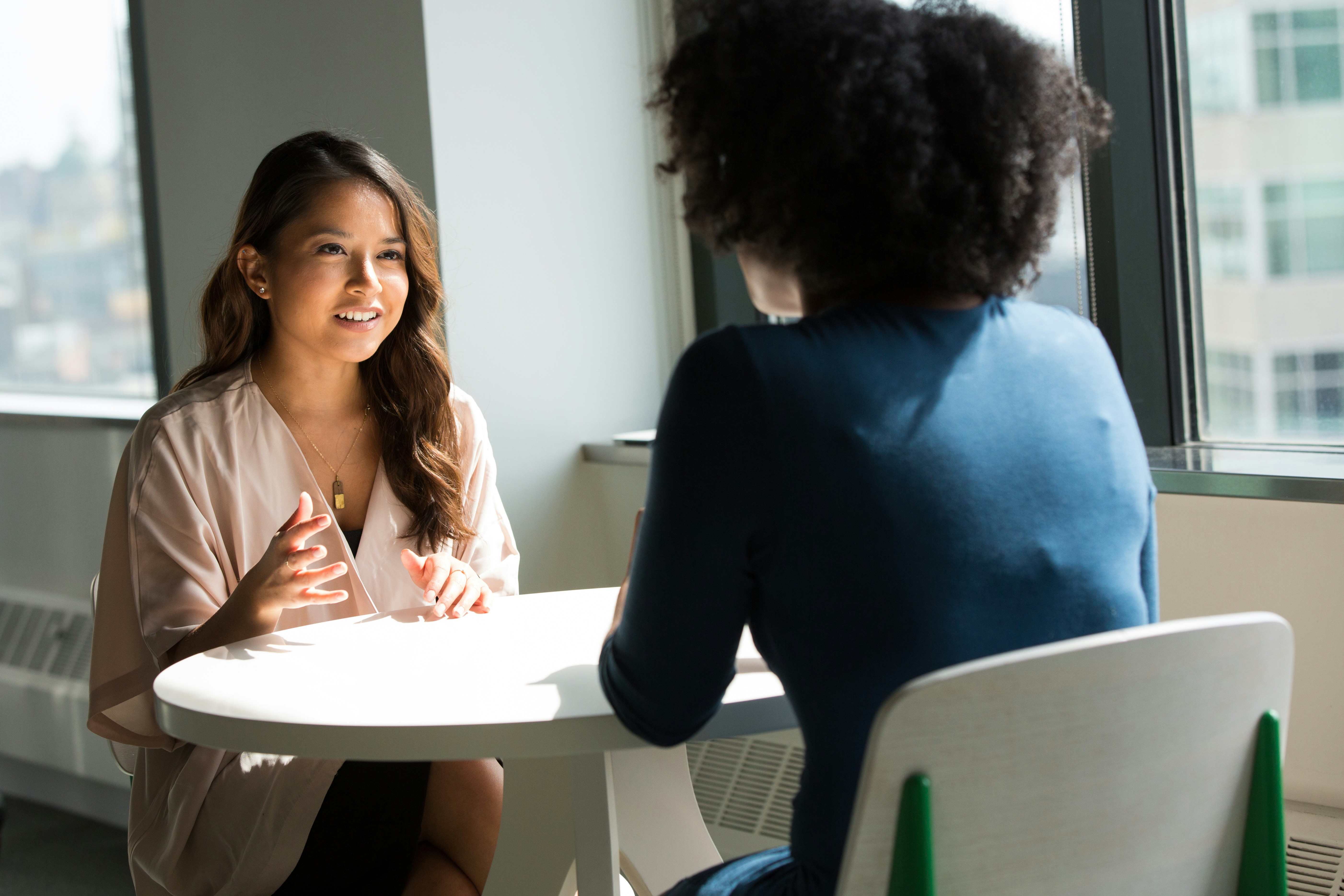 two women at a table having a conversation.