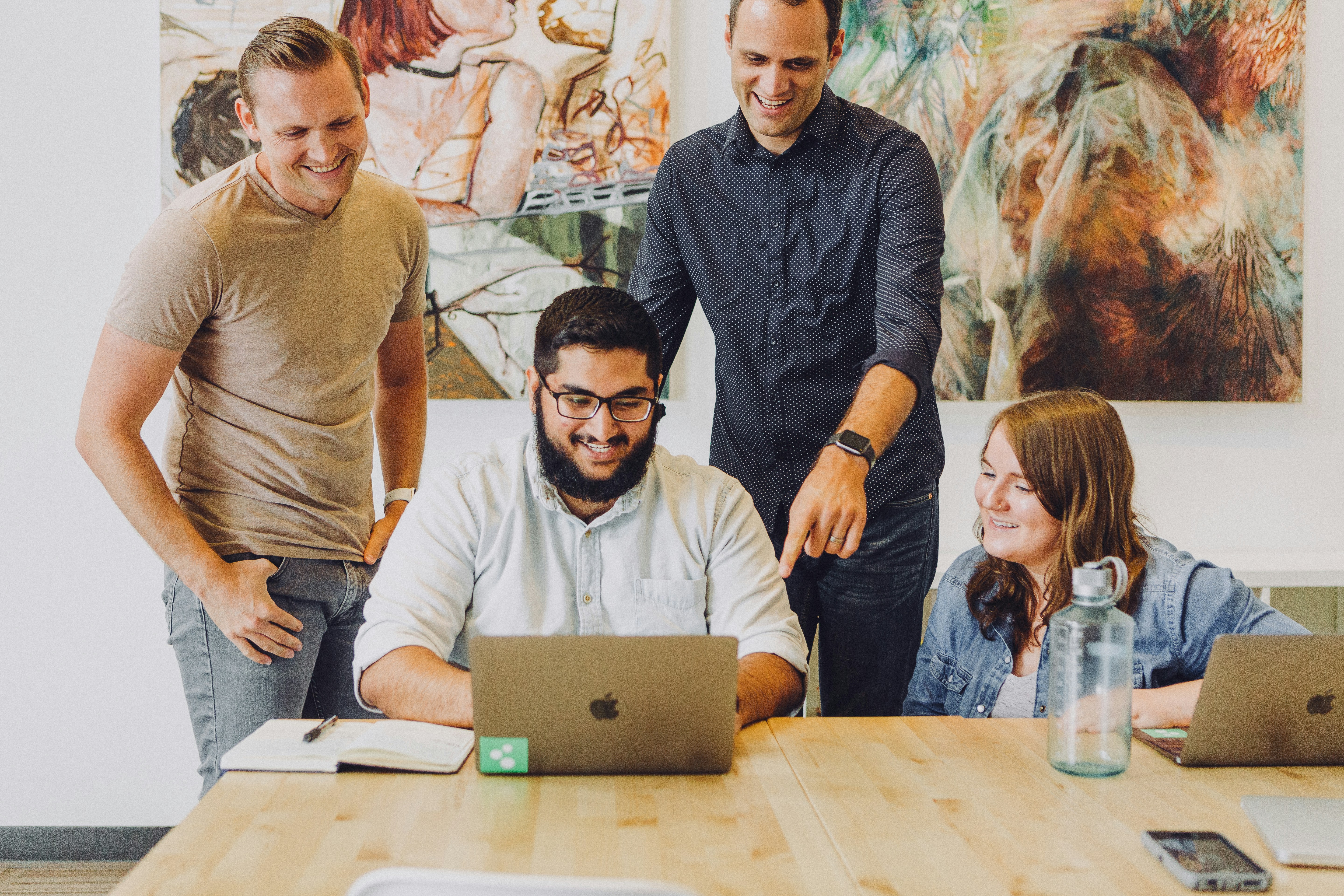 4 people at a table working together over a laptop