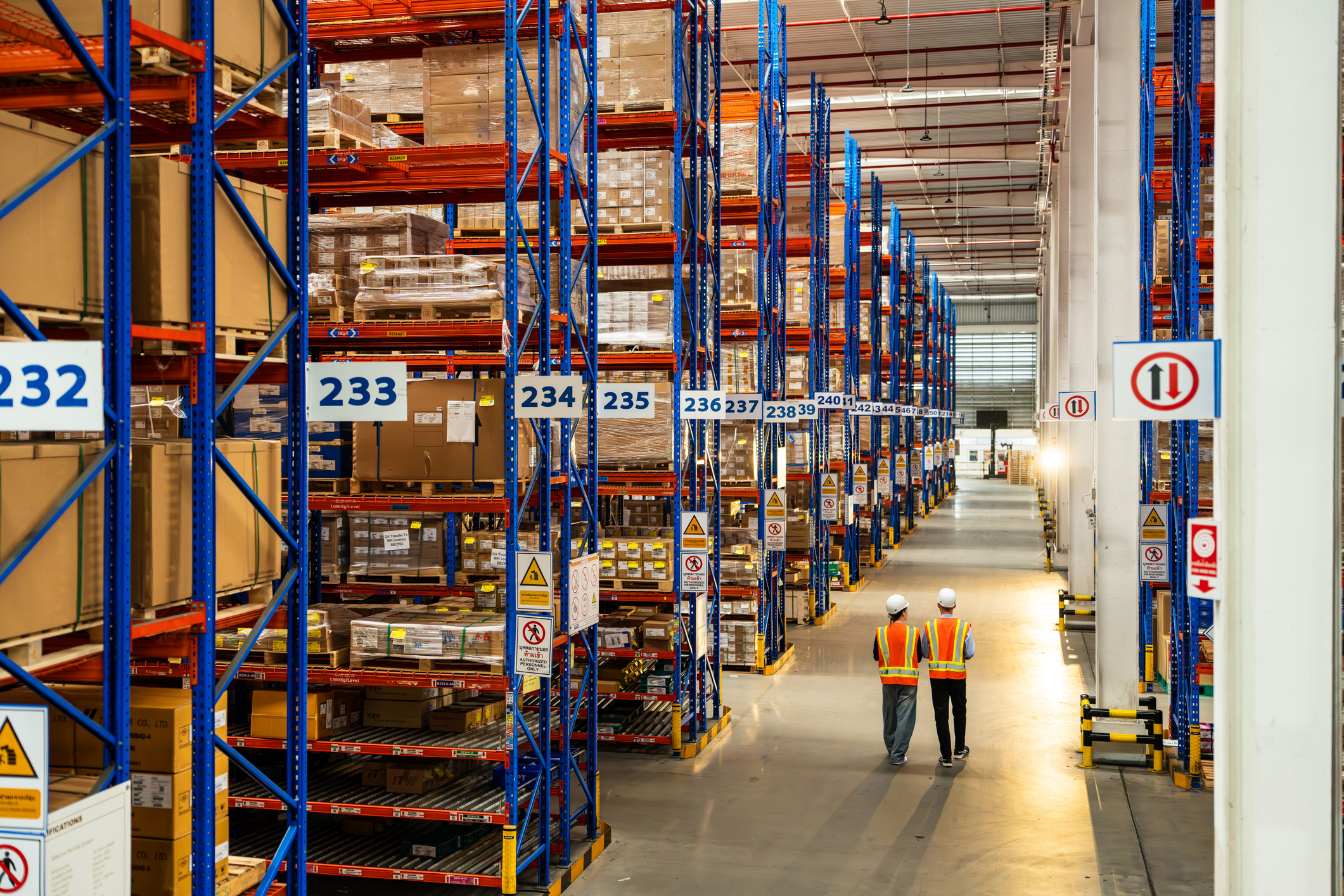 Organized Warehouse Shelves with Workers in Safety Gear Performing an Inspection