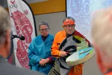 KPU Elder in Residence Lekeyten, holding a drum, stands with wife Cheryl Gabriel while offering a blessing.