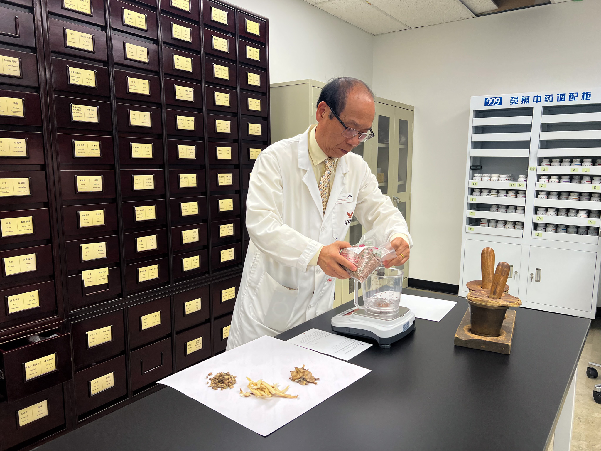 Dr. John Yang prepares herbs inside herbal dispensary.